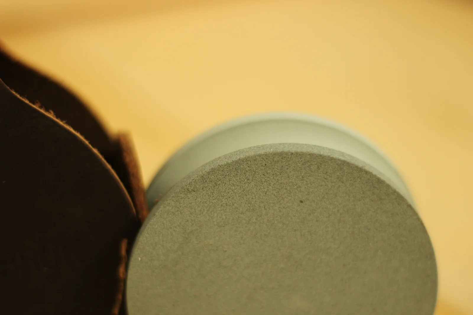 Macro close-up of the grinding stone abrasive surface showing fine grit particles bonded into the ceramic matrix