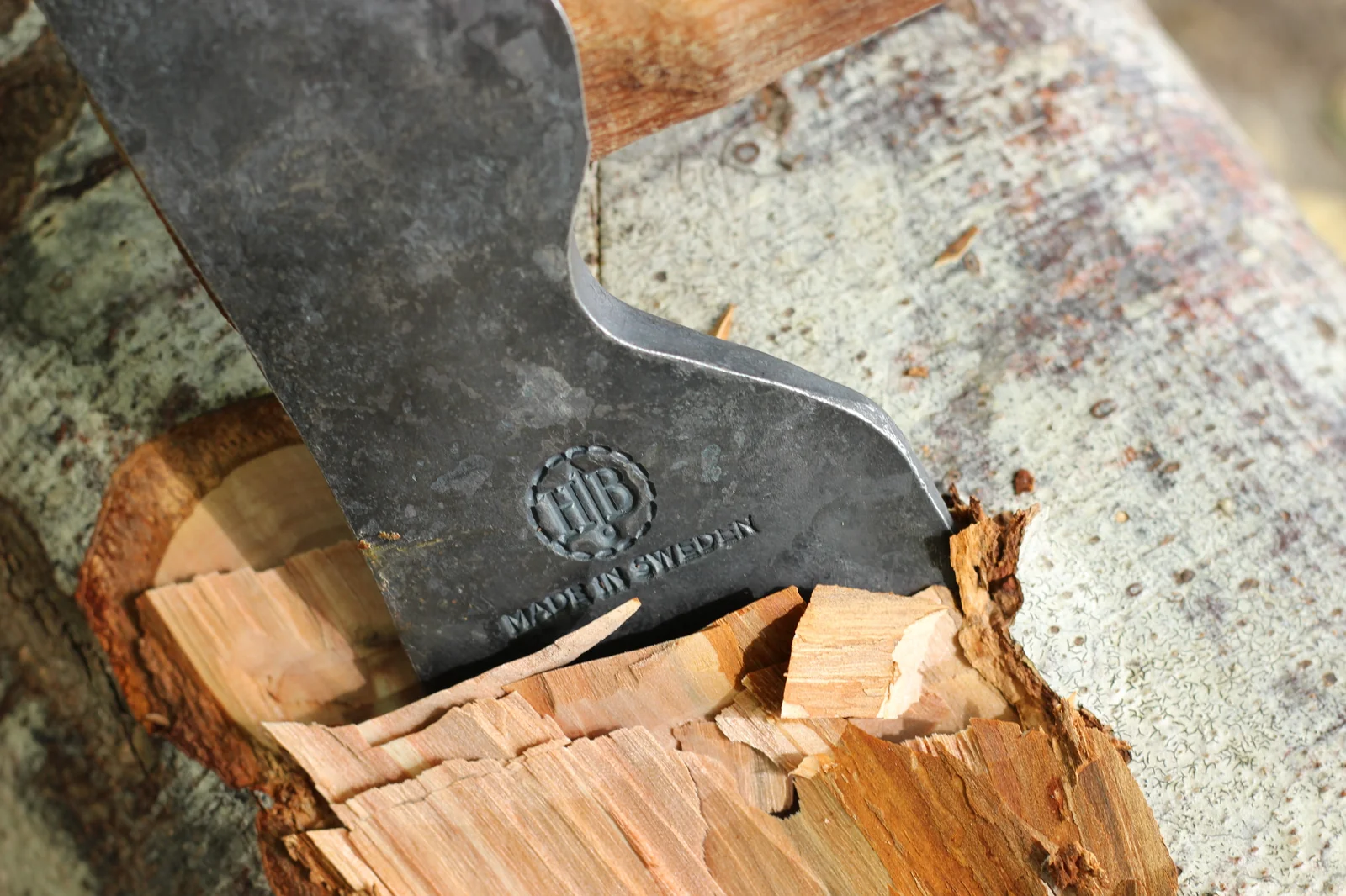 Close-up of the Hults Bruk HB stamp and MADE IN SWEDEN text on the axe head buried in birch wood