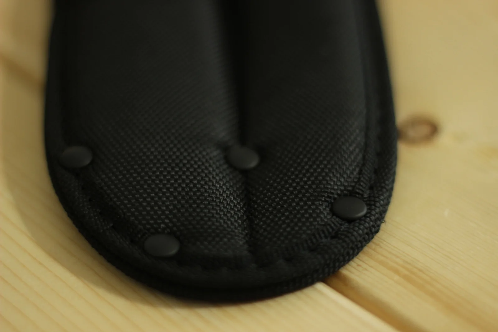 Close-up of the bottom of the nylon double sheath showing reinforcement rivets and the dual-blade-pocket construction