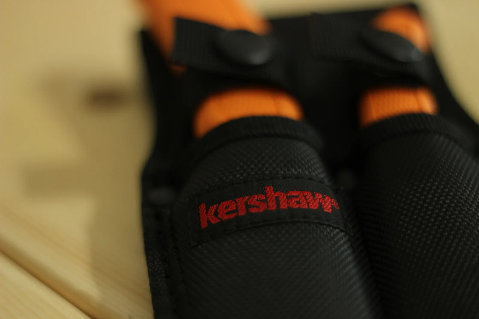 Top view of the sheath showing both retention straps snapped down over the two blaze-orange handles