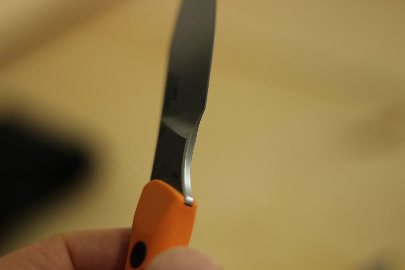 The 1882 blade held vertically showing the full clip-point profile with the concave dip along the spine where it transitions to the tip