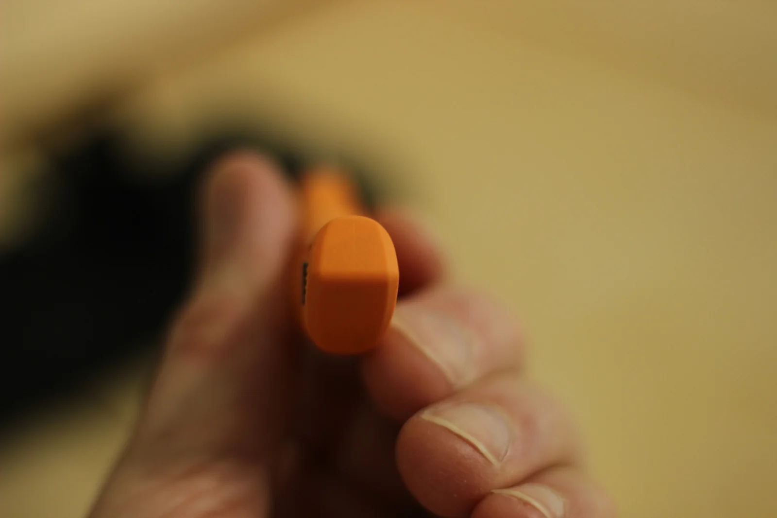 The 1882 handle pommel end showing the blaze-orange polypropylene shape from straight-on with the rubber overlay panel visible on the side