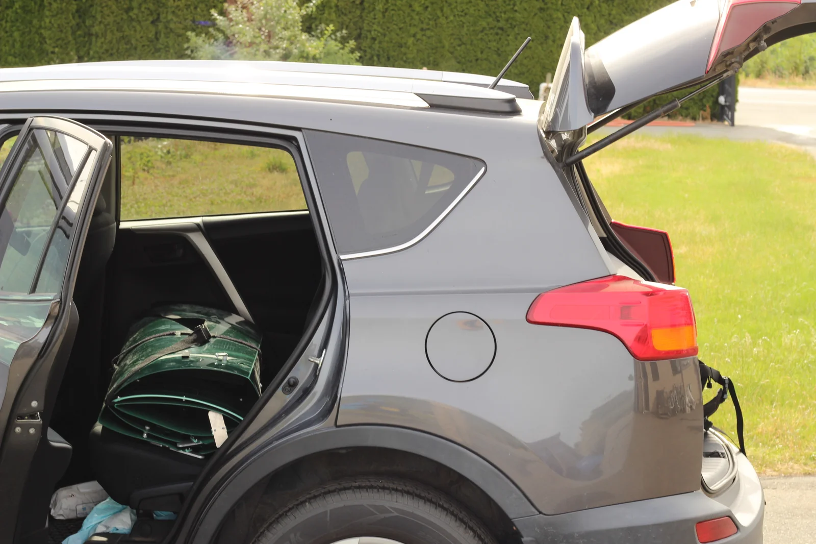 Folded green Tucktec Pro kayak loaded in the cargo area of a Toyota RAV4 SUV with the hatch open