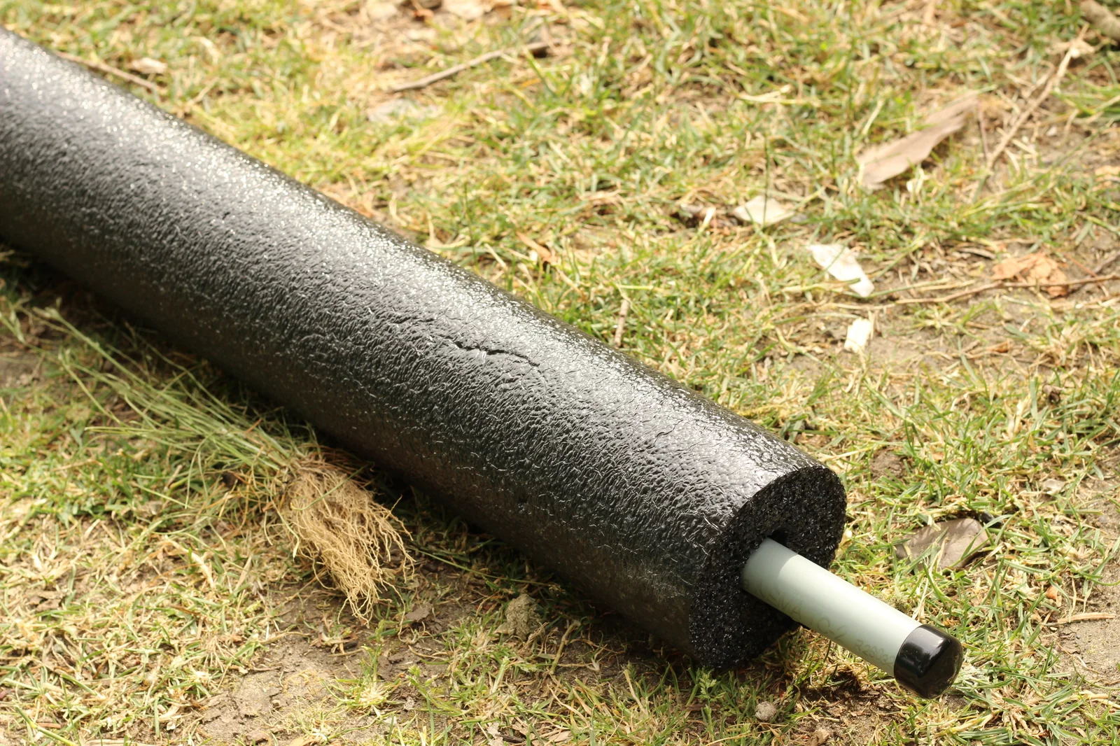 Black foam stabilizer pontoon on grass with the green plastic mounting insert visible at the end