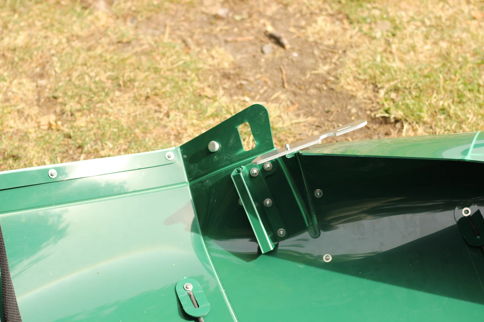 Aluminum locking lever being seated at the top of the green hull bulkhead with the mounting frame and rivets visible